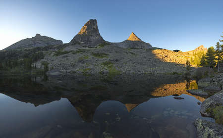 Russia. Krasnoyarsk Territory. Reflections of harsh rocks in the lakes of the Ergaki Natural Mountain Park.の写真素材