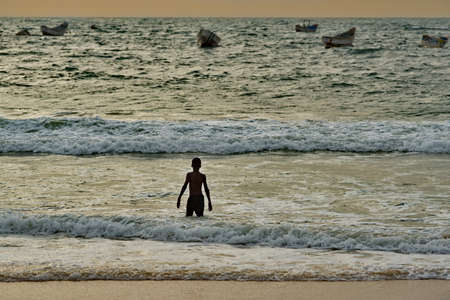Nouakchott. Mauritania. October 07, 2021. A little black boy is swimming near the Atlantic Ocean shore among the waves of a storm beginning at sunset.のeditorial素材
