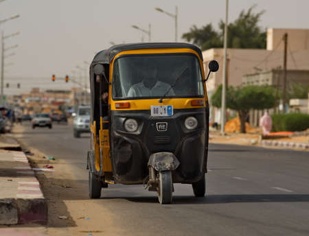 Nouakchott. Mauritania. October 09, 2021. An indoor three-wheeled yellow scooter transports locals...