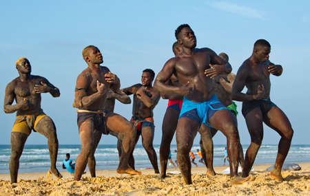 Dakar. Senegal. October 13, 2021. A group of Senegalese wrestling fighters Laamb on the sandy seashore conducts a ritual dance before the fight, showing the opponent strength.のeditorial素材