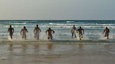 Dakar. Senegal. October 13, 2021. Muscular wrestlers ritually run out of the sea to the sandy shore with an abundance of water spray after the end of the Laamb wrestling competition.のeditorial素材