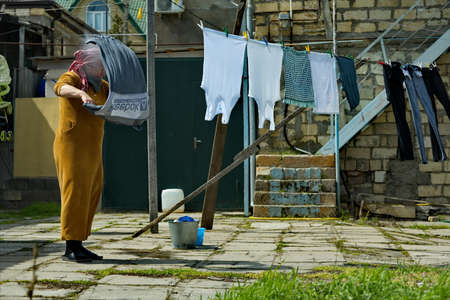 Derbent. Russia. April 09, 2021. A resident of an ancient city hangs her laundry on a drying rope in the courtyard of a residential building.のeditorial素材