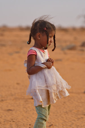 Shingetti. Mauritania. October 04, 2021. Portrait of a little African girl in a white dress and fancy pigtails on a morning walk in the Sahara Desert.のeditorial素材