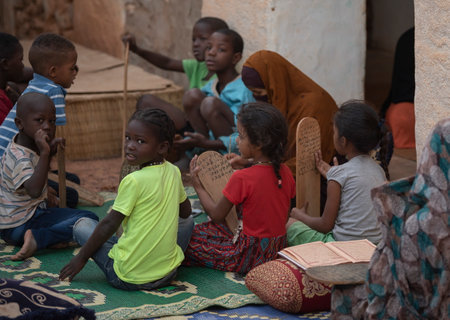 Shingetti. Mauritania. October 05, 2021. Little girls and boys are studying in a lesson at a local Koran school. The surahs of the Koran are written on wooden tablets in Arabic.のeditorial素材