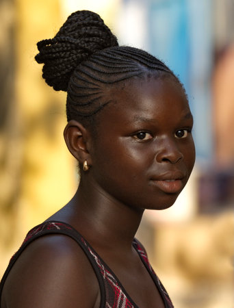 Joal. Senegal. October 15, 2021. Street portrait of an African girl near a residential building.のeditorial素材