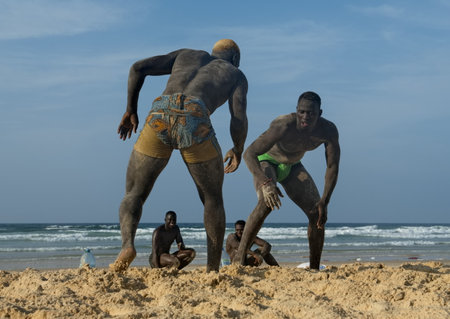 Dakar. Senegal. October 13, 2021. A group of Senegalese wrestling fighters Laamb on the sandy seashore conducts a ritual dance before the fight, showing the opponent strength.のeditorial素材