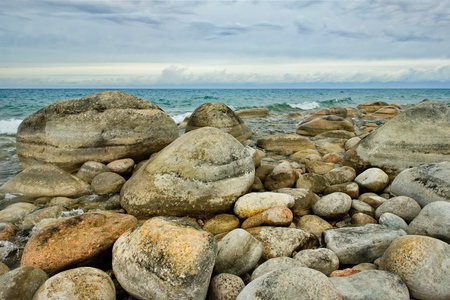 Northern Kyrgyzstan. The landscape of the cold Issyk-Kul lake with colored rounded stones of various sizes along the picturesque shore.の写真素材