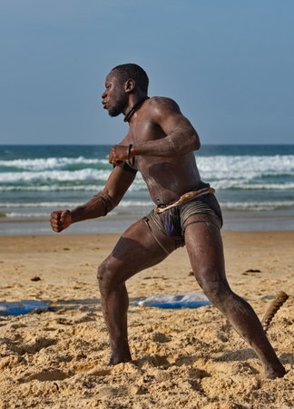 Dakar. Senegal. October 13, 2021. Senegalese wrestler Laambe holds a ritual ceremony on the seashore before the fight, demonstrating strength to his opponent.のeditorial素材