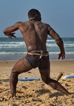 Dakar. Senegal. October 13, 2021. Senegalese wrestler Laambe holds a ritual ceremony on the seashore before the fight, demonstrating strength to his opponent.のeditorial素材