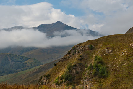 The high mountain peaks of the North Caucasus are surrounded by morning misty clouds hovering at...