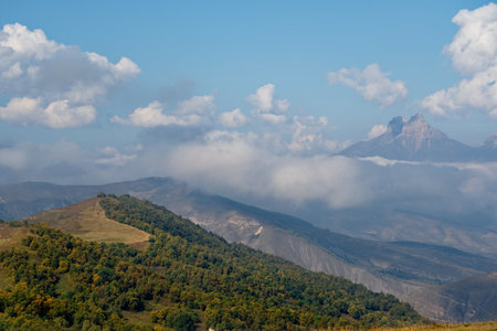 Russia. The Elbrus region. The high mountain peaks of the North Caucasus are surrounded by morning misty clouds hovering at different levels of inaccessible rocks.の写真素材