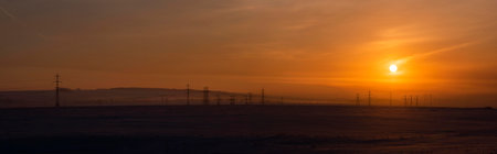 High-voltage metal structures against the background of a crimson dawn winter sky.