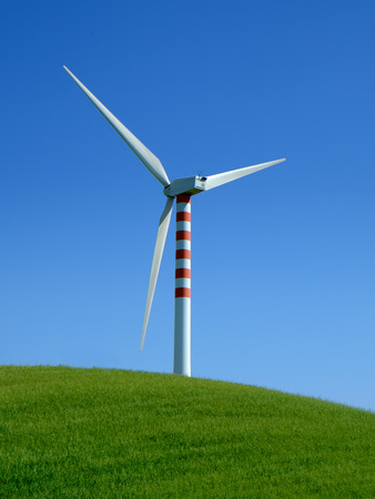 Wind turbine in a green field with blue sky