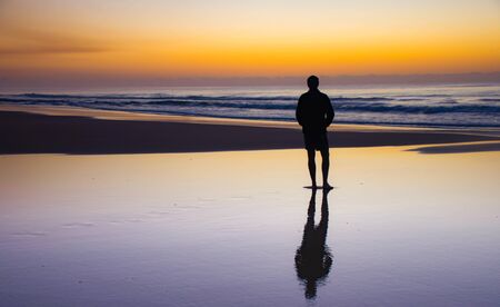 Colorful sunset at the beach of Fraser Island. Refections in the wet sand. Sillouette Person. High...