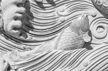 Background striped fish are swimming at the carving on the rock beautifully.の写真素材