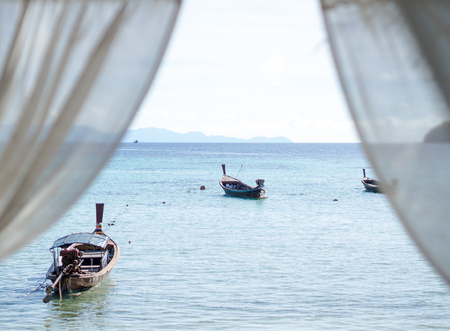 Sea and boats with skyline view from hotel room window and white curtain; selective focus on seaの写真素材