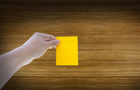 Sticky note on man hand with wooden backgroundの写真素材
