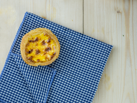 Egg tart on wood table with scott pattern napkin