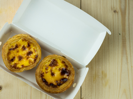 Egg tarts in a box on wood tableの写真素材