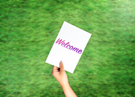 Welcome on card with hand holding on blurred grassの写真素材