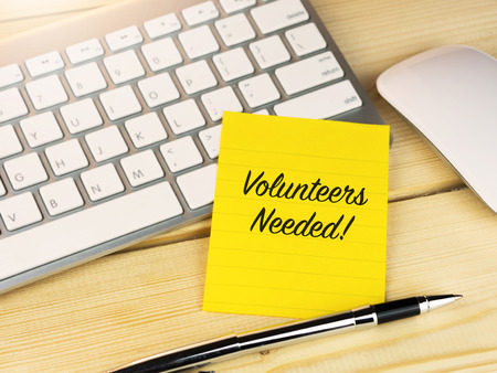 Volunteers needed on sticky note on work tableの写真素材