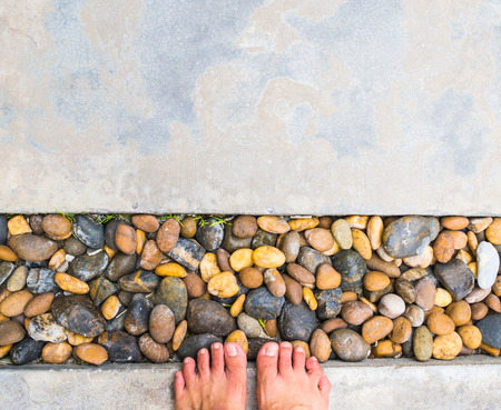 Stones and cement floor decoration with feet standing, looking downの写真素材