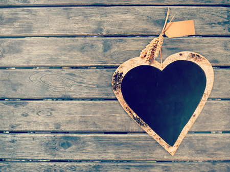 Heart shape black board on wooden wall, vintage color filtered, love concept backgroundの写真素材