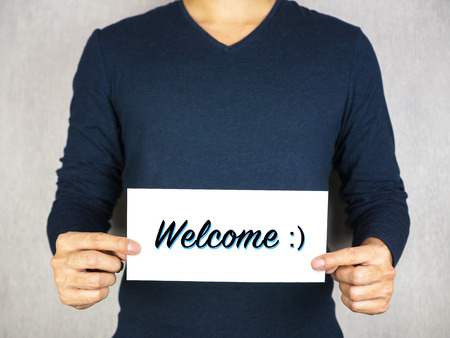 Welcome with smiley face icon sign holding by man, happy and greeting conceptの写真素材