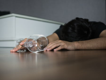 Empty wine glass fall down with man pass out on the floorの写真素材