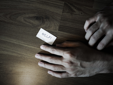 Hand on floor with help note, darkness filteredの写真素材