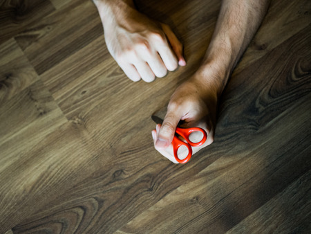 Scissor held in a hand, person commits and lying on the floorの写真素材