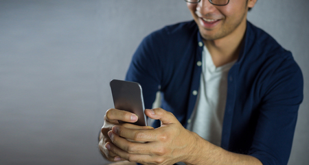 Men smiling using phone on grey backgroundの写真素材