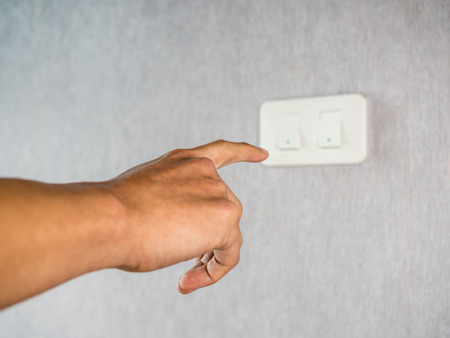 Turning of light switch on grey wallの写真素材