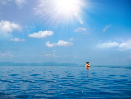 Infinity pool view with a man at the edge with sun lightの写真素材