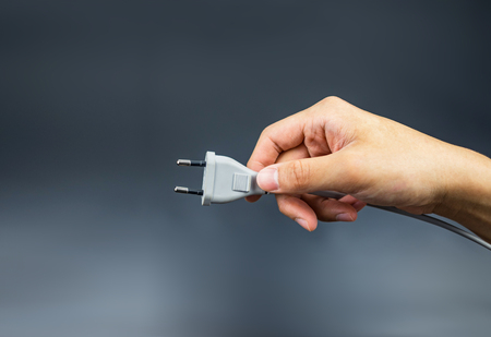 Plug hand holding on black backgroundの写真素材