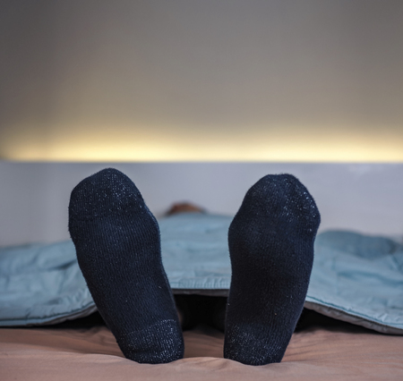 Feet wearing sock on bedの写真素材