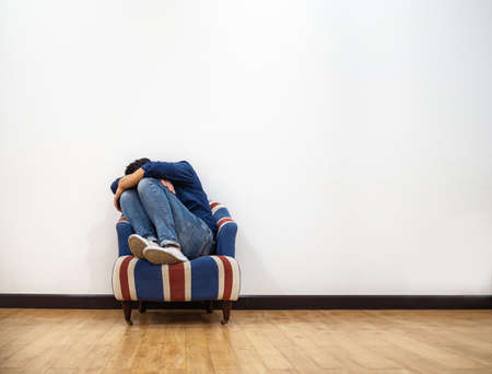Man hugging knees and crying on sofaの写真素材