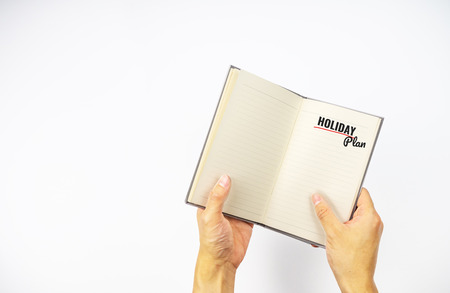 Holiday plan on notebook with hand holding on white backgroundの写真素材
