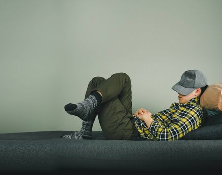 Man covering face with cap, and lying on sofaの写真素材