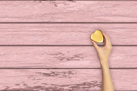 Gold Heart hand holding. on wooden table with spaceの写真素材