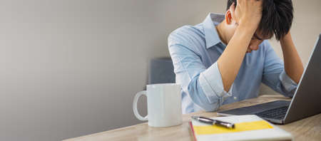 Stressed at work, man looking depressed on deskの写真素材