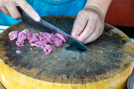 The meat vendor is cutting raw meat on the wood block in the market.の写真素材