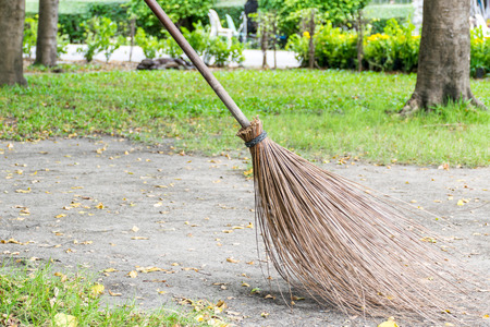Cleaning in the autumn park - broom and bench with pile of yellow fallen leavesの写真素材
