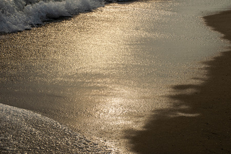 Close up shot of waves breaking on the sandy beach at sunriseの写真素材