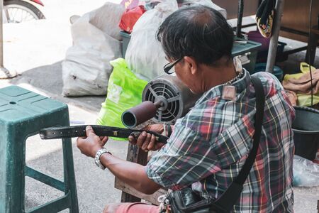 Songkhla, Thailand, May 1, 2018 : Unknown Shoe-Belt repairs repairing a belt on the sidewalk by the street in hat yai, Songkhla, Thailand.のeditorial素材