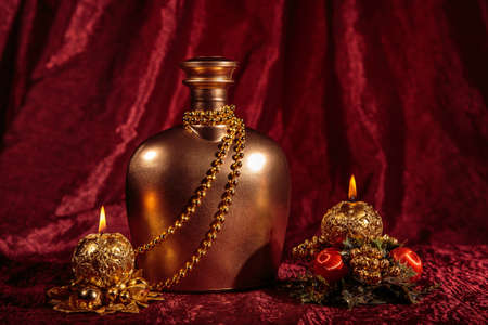 A bottle of brandy and two candles in New Year and Christmas on red background