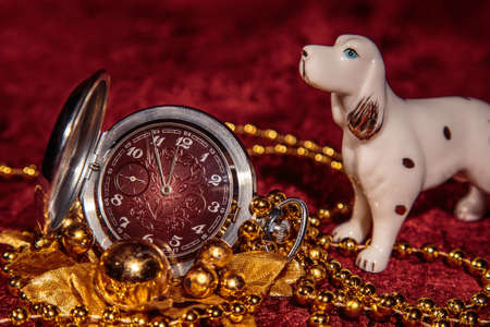 Christmas still life with metal pocket watch and porcelain dog on Burgundy backgroundの写真素材