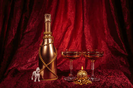 New year Bottle of champagne and candle, glasses and dog on redの写真素材