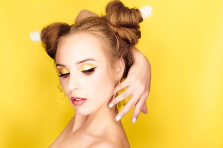 Young beauty girl with hair horns electic lamp hairstyle on a yellow backgroundの写真素材