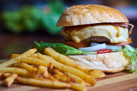 Cheese burger - American cheese burger with Golden French fries on wooden boardの写真素材